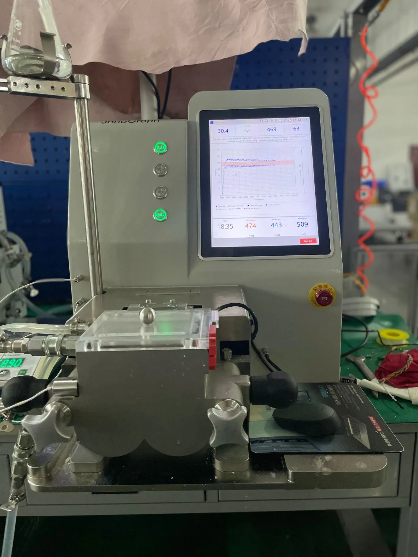 JenoGraph machine shown from the front in a laboratory setup, with its touchscreen and sample area visible.