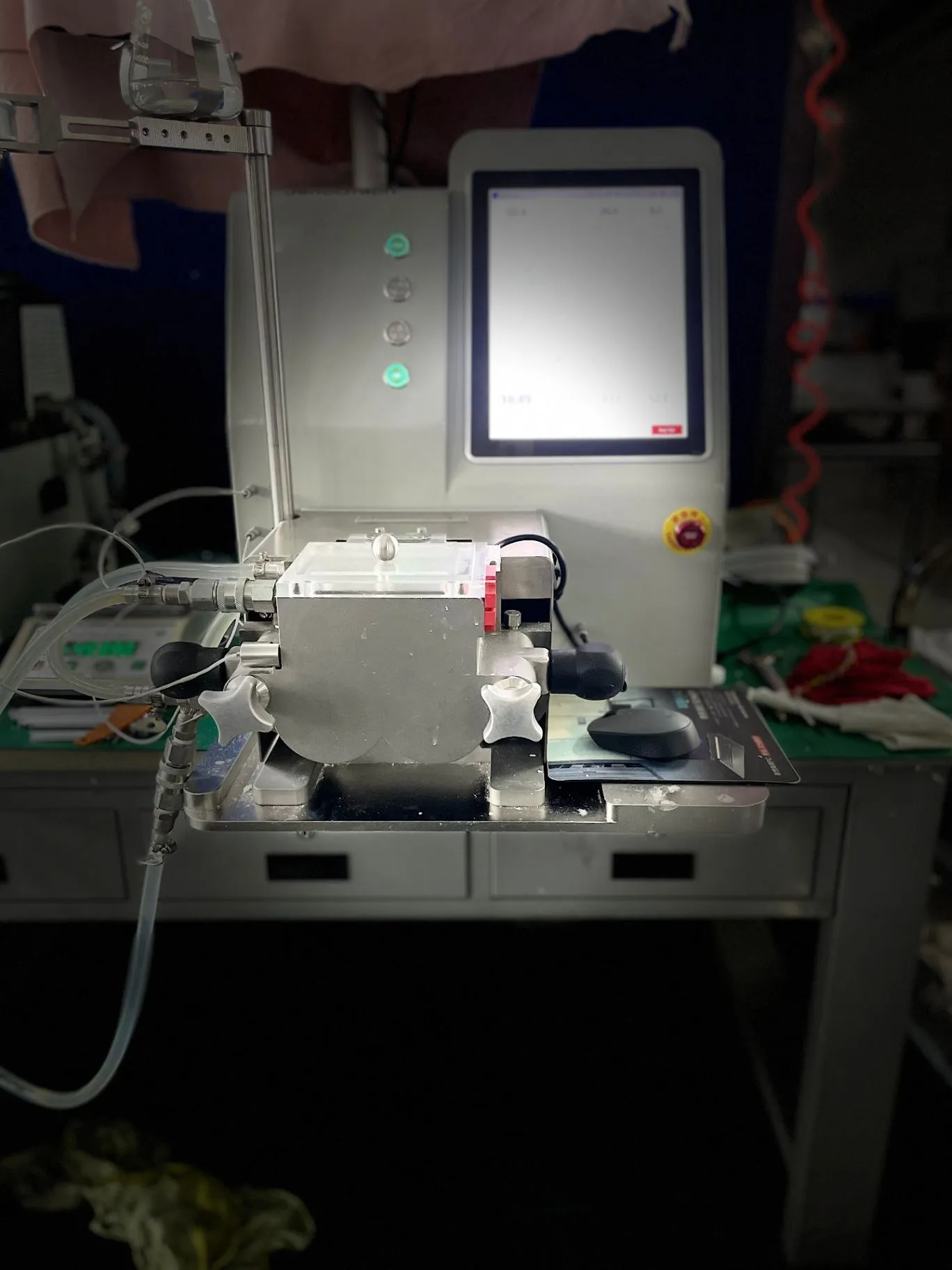 JenoGraph machine photographed at an angle, showing the enclosed sample area, touchscreen, and connected tubing.