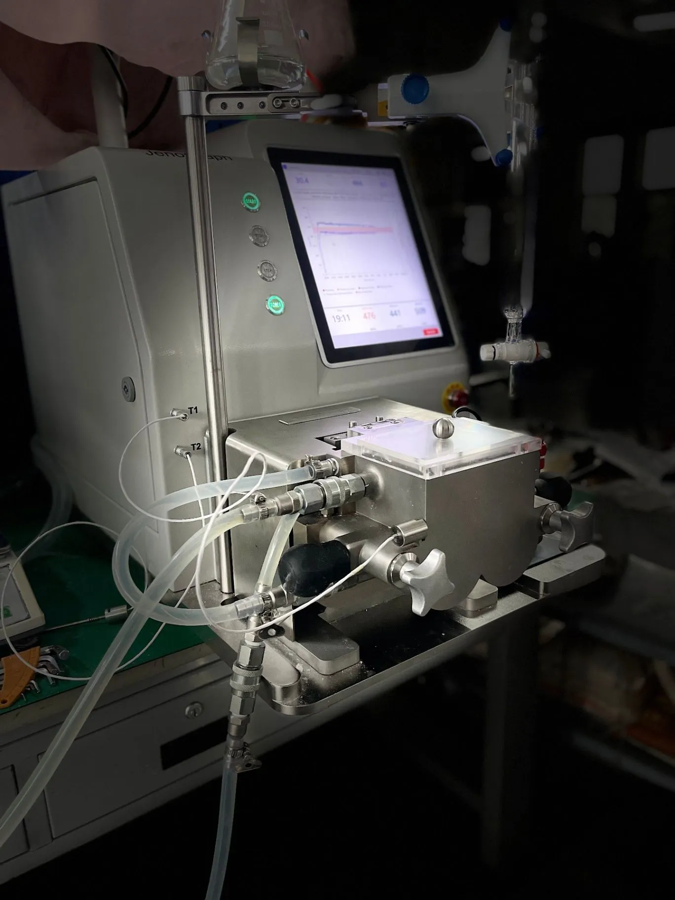 Side view of the JenoGraph machine in a laboratory, with the sample area and touchscreen in view.