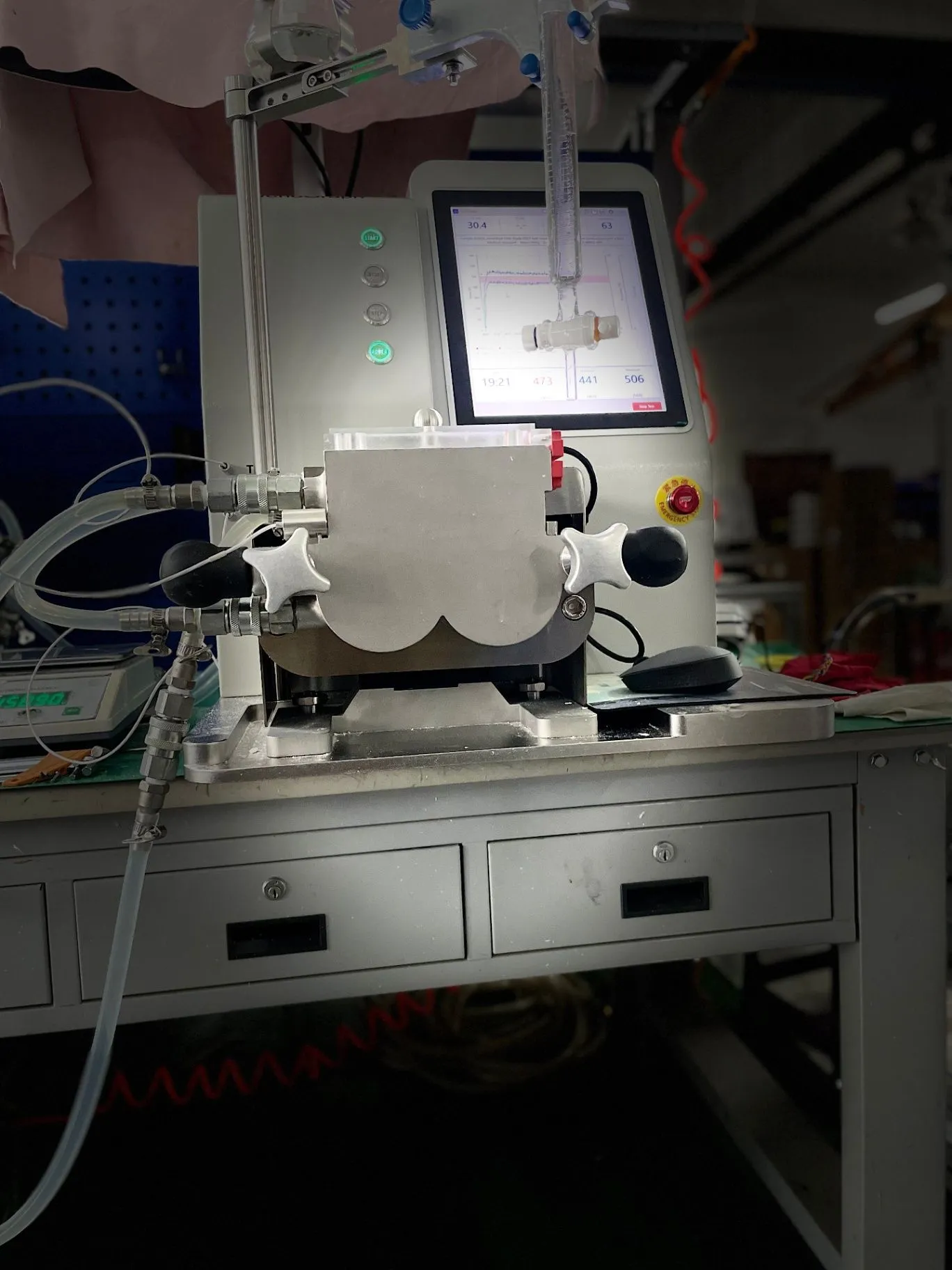 Front view of the JenoGraph machine with a clear upper sample fixture above the enclosed sample area.