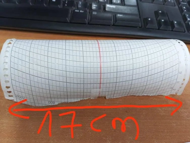 A roll of grid-marked recording paper on a wooden desk below a keyboard.